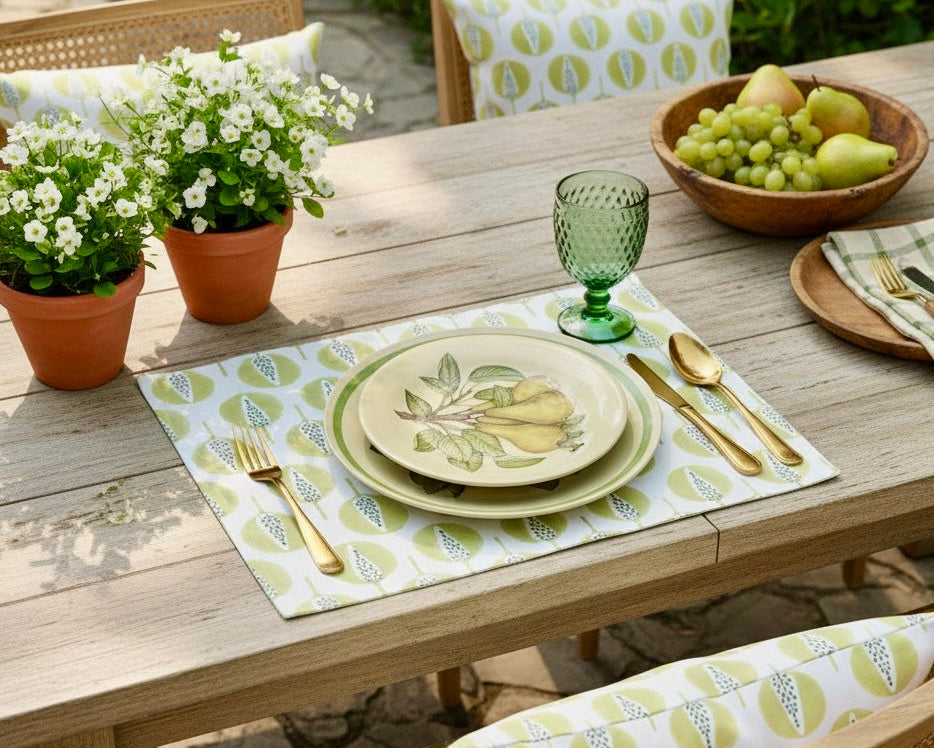 Outdoor dining table setting with plates, glasses, and utensils on a placemat.